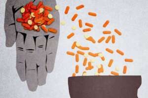 A hand pouring pills into a person's head